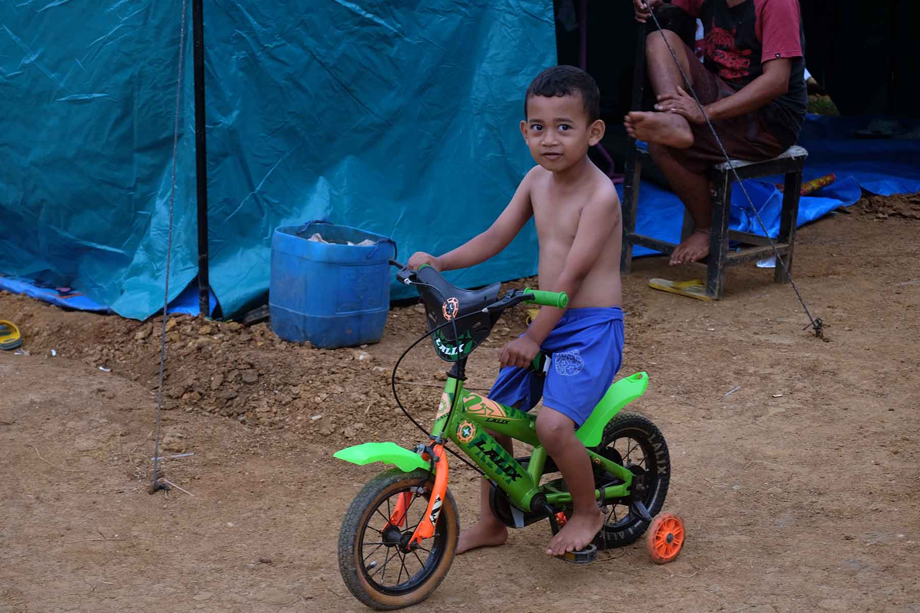 Bocah ini bernain sepeda di depan tenda pengungsian. (Foto: Ronny Adolof Buol)