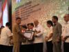 Suasana saat Gubernur Sulut, Olly Dondokambey menyerahkan piagam penghargaan kepada Pj. Wali Kota Kotamobagu, Asripan Nani, (Foto: Diskominfo KK).