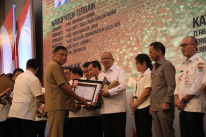 Suasana saat Gubernur Sulut, Olly Dondokambey menyerahkan piagam penghargaan kepada Pj. Wali Kota Kotamobagu, Asripan Nani, (Foto: Diskominfo KK).