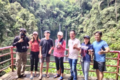 Satfsus Gubernur Sulut bidang Pariwisata, Dino Gobel bersama para influencer Sulut berpose dengan latar belakang air terjun Tinoor. (foto:ist).