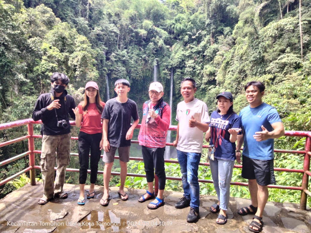 Satfsus Gubernur Sulut bidang Pariwisata, Dino Gobel bersama para influencer Sulut berpose dengan latar belakang air terjun Tinoor. (foto:ist).
