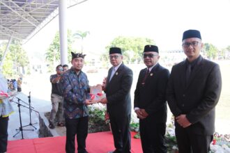 Murdiono saat menyerahkan buku perlawanan rakyat di pedalaman mongondow tahun 1902 secara sembolis kepada pj. Wali kota kotamobagu, abdullah mokoginta, (foto: diskominfo kk).