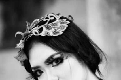 Black and white portrait of a woman with dramatic makeup holding flowers.